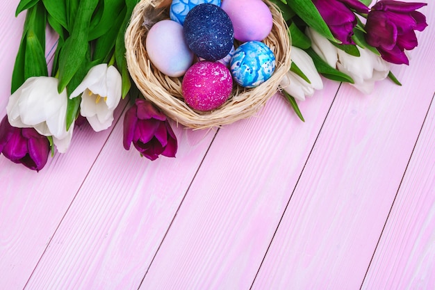 Easter eggs in a nest and tulips on wooden planks