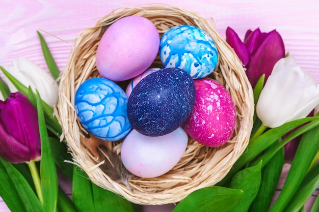 Easter eggs in a nest and tulips on wooden planks