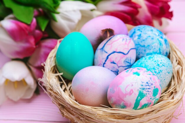 Easter eggs in a nest and tulips on wooden planks