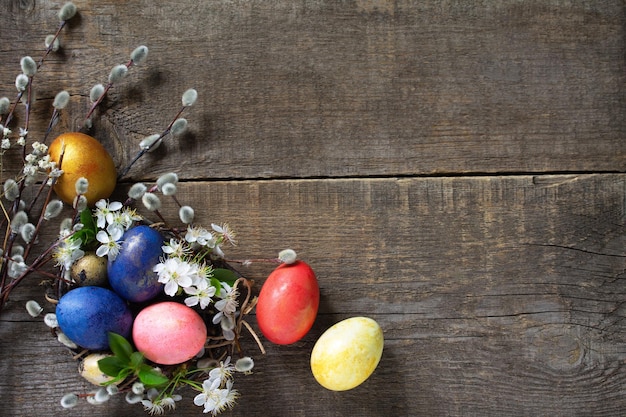 Easter eggs in a nest with willow branches and spring flowers Top view flat lay