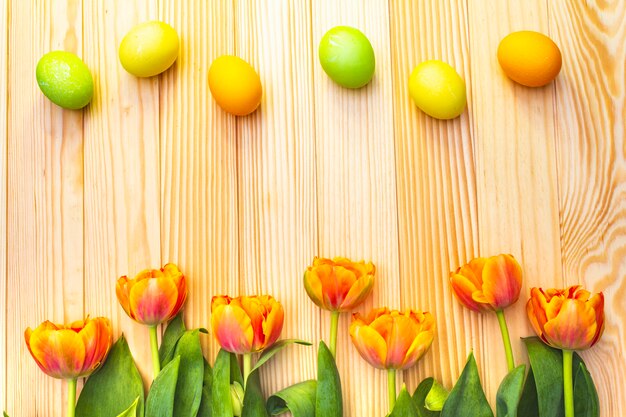 Easter eggs and orange tulip flowers on a wooden table