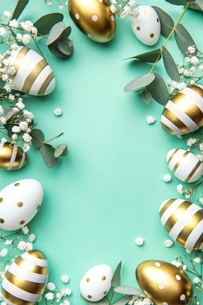 Easter eggs painted in gold and eucalyptus branches on a soft green background