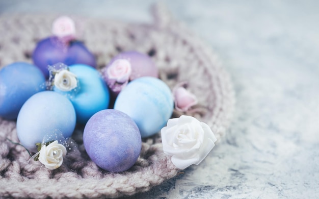 Easter eggs painted in soft pastel colors felt flowers copy space gray concrete