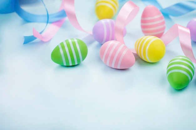 Easter eggs in pastel colors on light blue background with ribbons