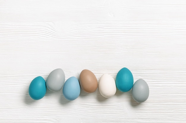 Easter eggs pastel colors lined up row on white wood Easter celebration card with dyed chicken egg