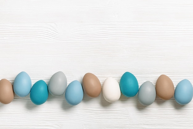 Easter eggs pastel colors lined up row on white wooden background with copy space Easter celebration