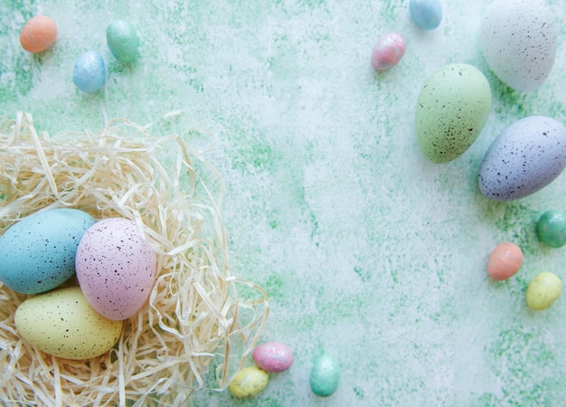 Easter eggs in straw nest on a green wooden background