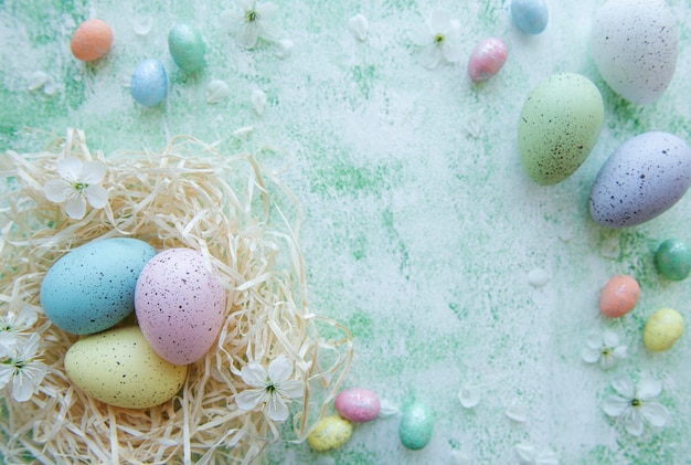 Easter eggs in straw nest on a green wooden background