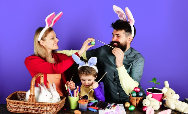 Easter family traditions mother father and son painting eggs for holidays happy family in bunny ears