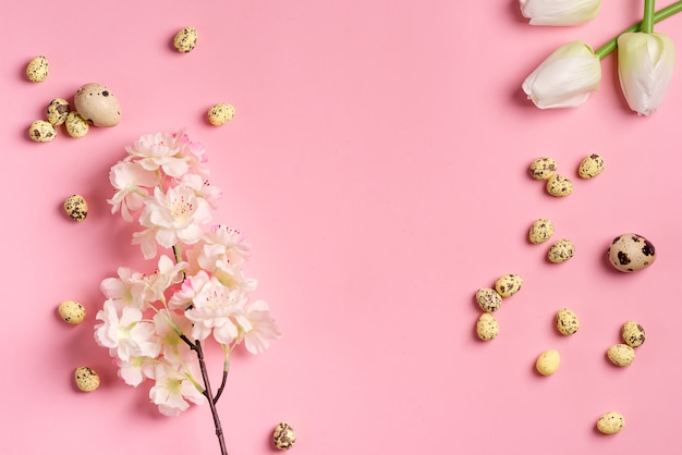 Easter festive composition from quail eggs, fresh tulips and cherries branch on pink.