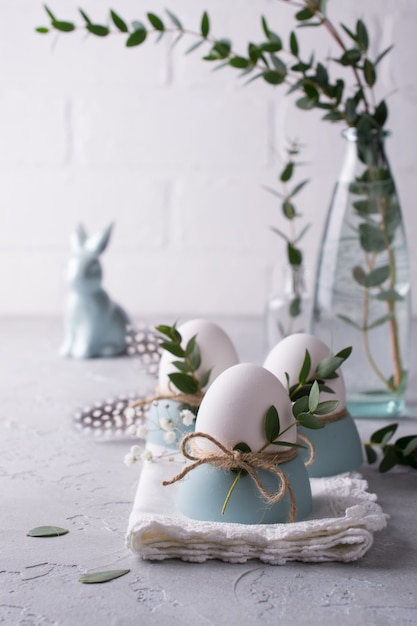 Easter  festive table setting with white chicken  eggs in eggs cups, leaf sprigs of eucalyptus. .