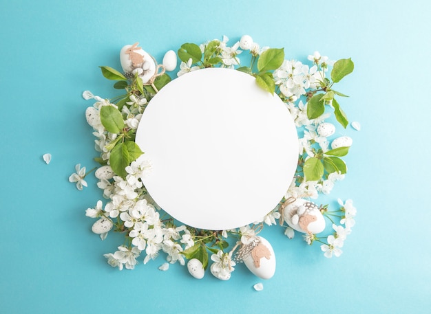 Easter  floral eggs composition with paper round blank in the centre of blue background