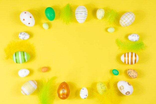 Easter frame with eggs and feathers on a yellow background Minimal concept View from above Card with copy space for text