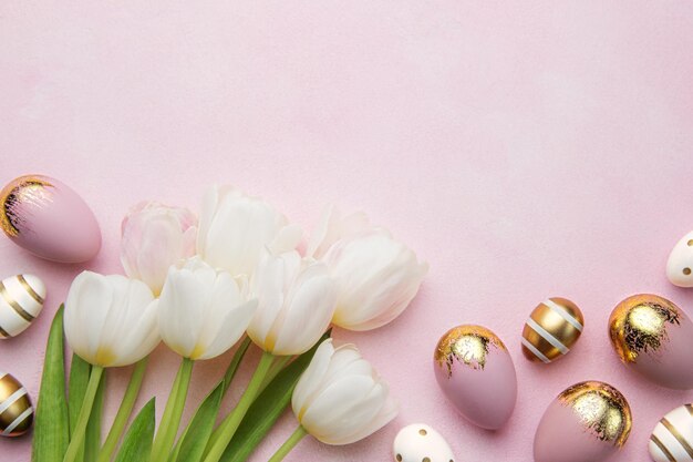 Easter golden eggs and pink tulips on pink background