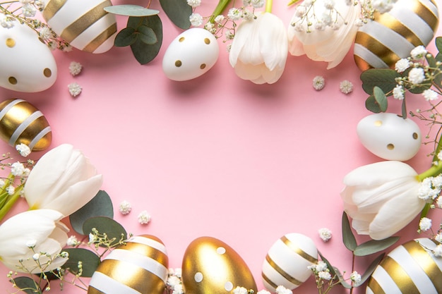 Easter golden eggs and white tulips on pink background