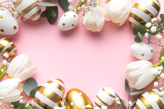 Easter golden eggs and white tulips on pink background