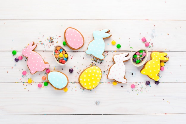 Easter greetings card with colorful gingerbread and sweets On a white wooden background Top view Free space for your text