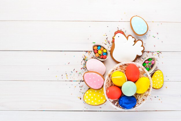 Easter greetings card with colorful gingerbread and sweets On a white wooden background Top view Free space for your text