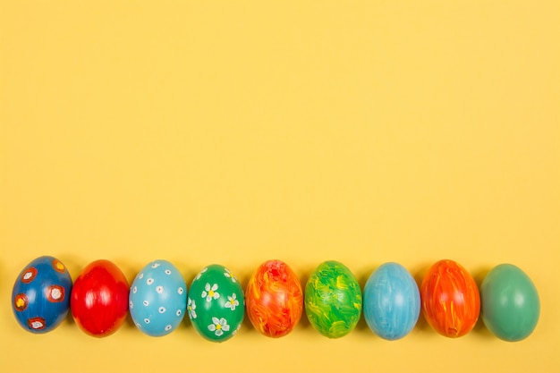 Easter holiday background. Coloured decorated easter eggs on a bright yellow background