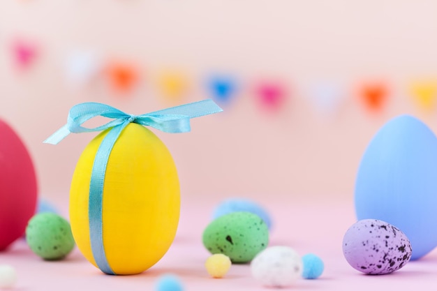 Easter holiday concept with colorful decorate Easter yellow egg with copy space on pink background.