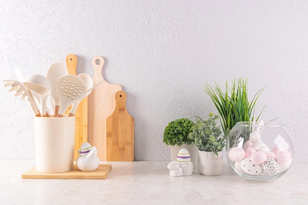 Easter holiday decorations on a light kitchen countertop with ecofriendly kitchen utensils and green plants in pots Easter concept