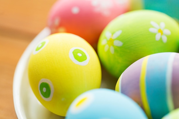 easter, holidays, tradition and object concept - close up of colored easter eggs on plate