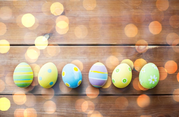 easter, holidays, tradition and object concept - close up of colored easter eggs on wooden surface with copy space