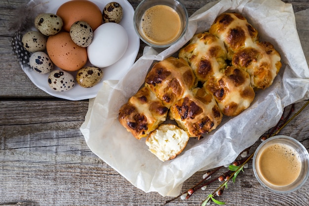 Easter hot cross buns with eggs rustic wood background