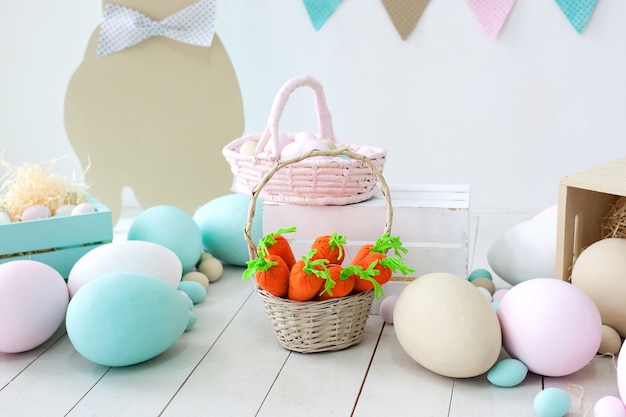 Easter! A lot of colorful Easter eggs! Easter decoration of a room with rabbits and baskets with eggs. Farm. harvesting. Basket with carrots and easter bunnies. Easter decor. Holiday flags on wall