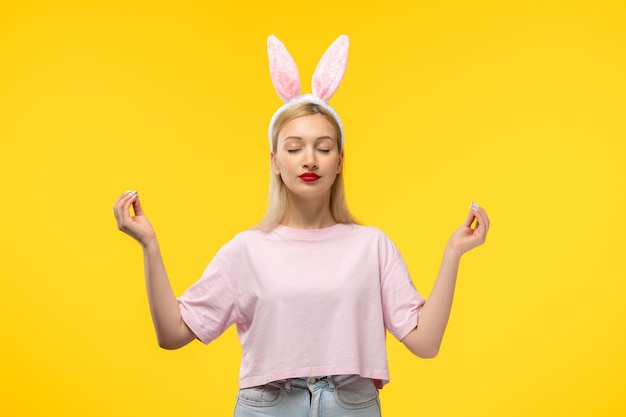 Easter lovely blonde adorable girl with pink bunny ears and red lipstick showing zen gesture