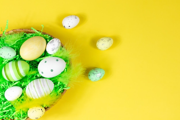 Easter nest with eggs and feathers on a yellow background View from above Place for text lettering Easter concept