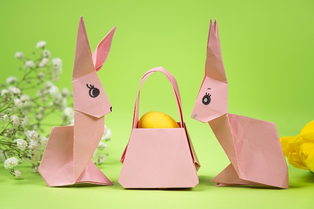 Easter origami two paper bunnies and an egg green background