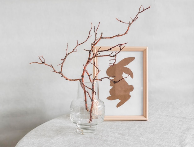 Easter still life a homemade painting with a paper rabbit and tree branches in a glass vase on the table