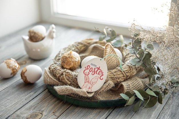 Easter still life with decorated Easter eggs and decorative nest on a wooden surface. Happy Easter wishes concept.