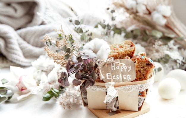 Easter still life with pieces of festive cupcake, eggs and flowers on a blurred light background. Easter holiday concept.