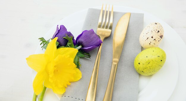 Easter table setting Easter eggs Spring flowers decoration napkin and cutlery on white