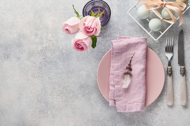 Easter table setting with floral decor on grey table. Elegance dinner. Top view.