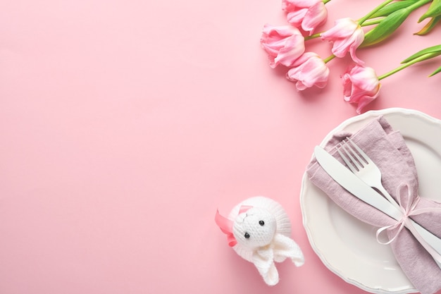 Easter table setting with floral decor on pink table. Elegance dinner. Mock up. Top view.