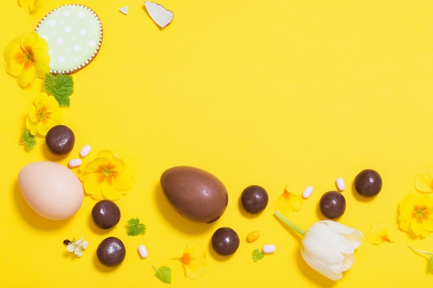 Easter yellow background with chocolatte eggs,    candy and spri