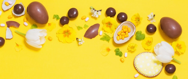 Easter yellow background with chocolatte eggs,    candy and spri