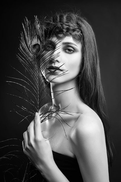 Eastern Arab woman with a peacock feather in her hands near her face. Beauty fashion makeup Arab women, big beautiful eyes. Beautiful smooth skin, peacock feather near eyes