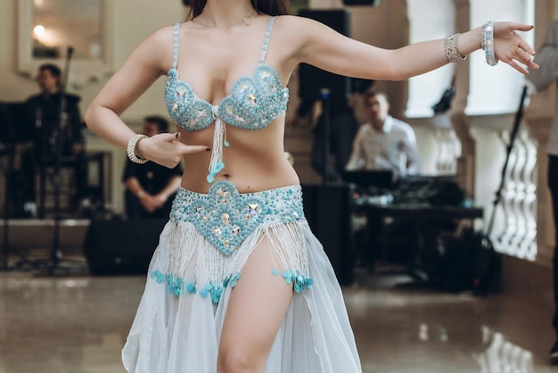 Eastern dancing sexy woman in blue costume performing eastern dance belly dancer beautiful woman dancing at wedding reception in restaurant