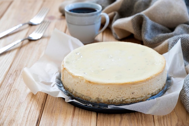 Easy recipe of classic New York cheesecake on parchment with coffee cup and forks on background Homemade festive pastry