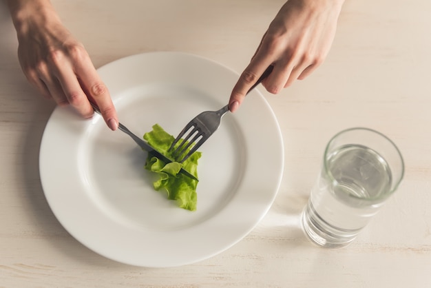 Eating disorder. Cropped image of girl eating lettuce.