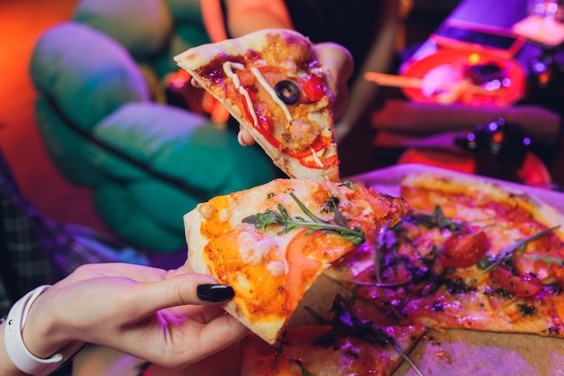 Eating food closeup of people hands taking slices of pepperoni pizza