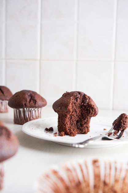 Eating muffins with a fork Muffins in paper cups on a plate Breakfast time White kitchen background.