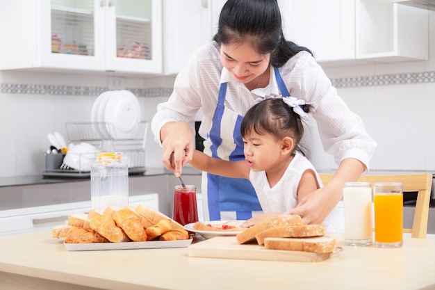 Eating and people concept - Asian happy mother and daughter having breakfast at home.