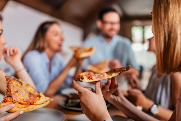 Eating pizza with friends. Close-up.