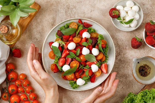 Eating Summer fresh diet salad with mozzarella cheese cherry tomatoes strawberry basil