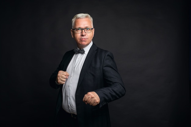 eccentric middle-aged gray-haired man in a strict suit stands in a fighting stance.